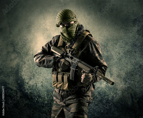 Portrait of a heavily armed masked soldier with grungy background