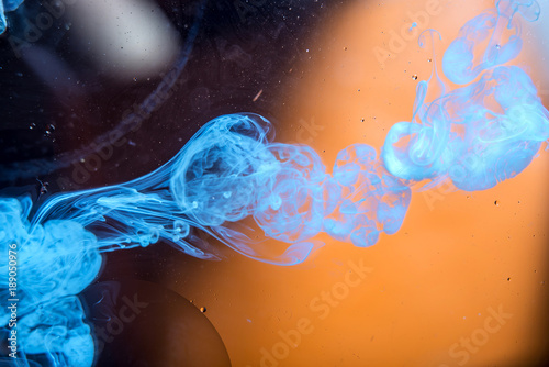 Swirls of white paint moving in the water like smoke on a orange background. Abstract background