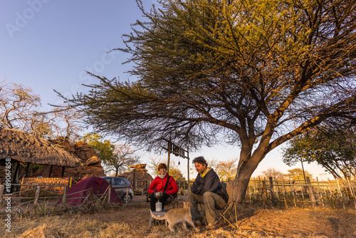 Couple selfie having breakfast, camping outdoors, morning cold. Travel adventure in Kruger National Park, South Africa.