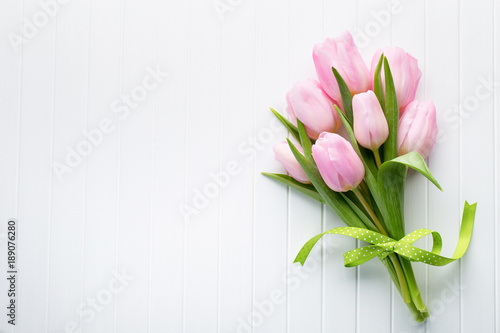 Fresh red tulip flowers bouquet on shelf in front of wooden wall.