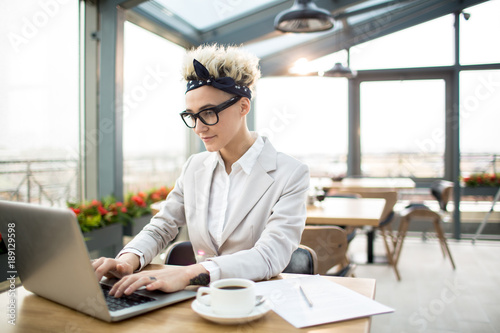 Young elegant businesswoman working in the net while sitting in cafe