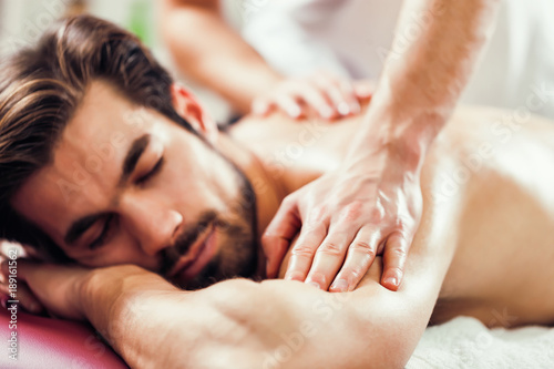 Młody człowiek cieszy się masaż na zabiegi spa.