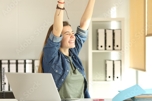 Satisfied intern raising arms at office