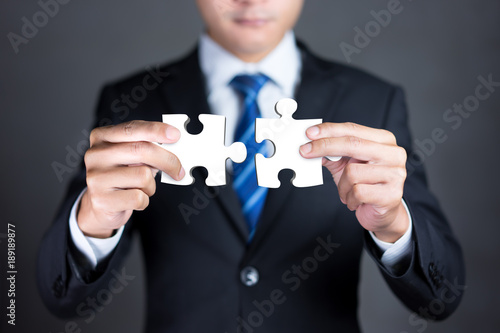 Businessman hands connecting puzzle pieces representing the merging of two companies or joint venture, partnership, Mergers and acquisition concept.