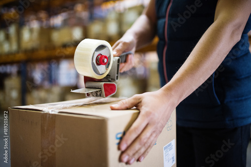 Male warehouse worker sealing cardboard boxes.