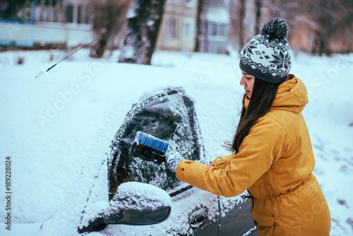 young woman clean car after snow storm