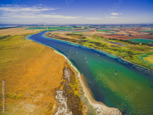 Aerial view of Werribee river with boats flowing among fields, meadows and pastures on bright summer day