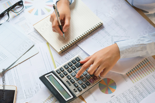 accountant working on desk to using calculator with pen on book .concept finance