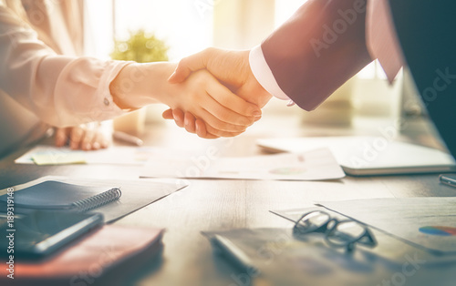 Businessman and businesswoman shaking hands above desk