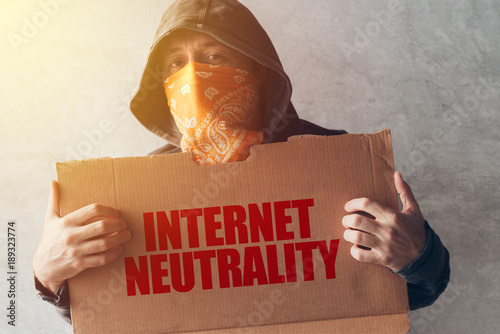 Hooded activist protestor holding Internet neutrality protest sign