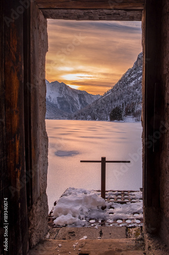 Sunset over frozen and snow covered lake Predil in winter