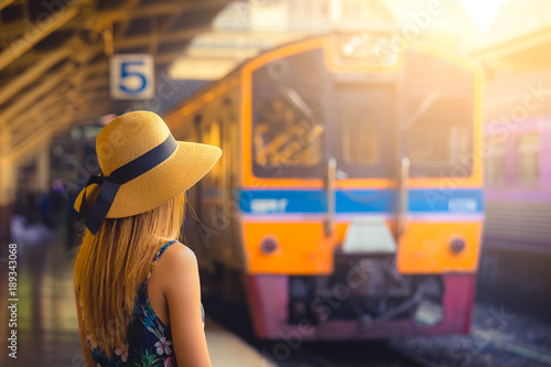 Woman with hat near railroad tracks waiting for train