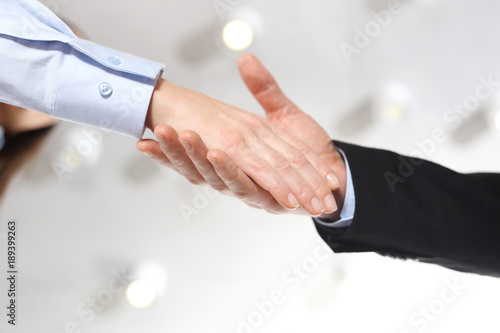 Praca zespołowa, gratulacje sukcesu. Dłoń kobiety i mężczyzny w strojach biurowych podczas gestu przywitania.
