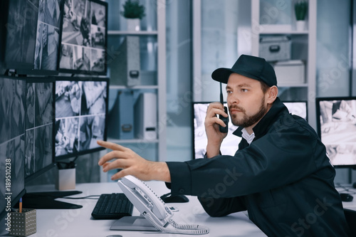 Male security guard using radio transmitter in surveillance room