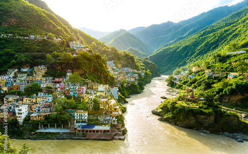 Confluence of two rivers Alaknanda and Bhagirathi give rise to the holy river of Ganga / Ganges at one of the five Prayags called Dev Prayag. Lush greenery in monsoons on the mountains. sunrise. India