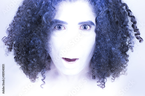 A noseless surprised man like alien with white skin and blue curly hair