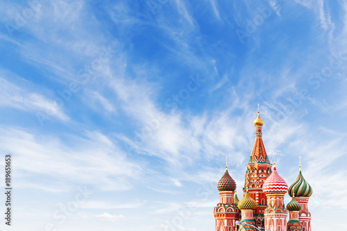 Domes of Saint Basil Cathedral on blue sky background. Famous landmark of Moscow, Russia. Bright sunny day with clouds. Cloudscape on blue sky. Place for text.