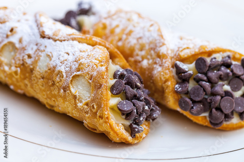 Italian cannoli on white plate with blackberries and chocolate chips