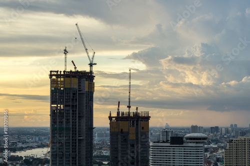 Bangkok city - construction of a two high-rise silhouette building with a crane on sunset sky background , cityscape bangkok Thailand