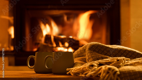 Steam from a cups with a hot cocoa on the fireplace background. 