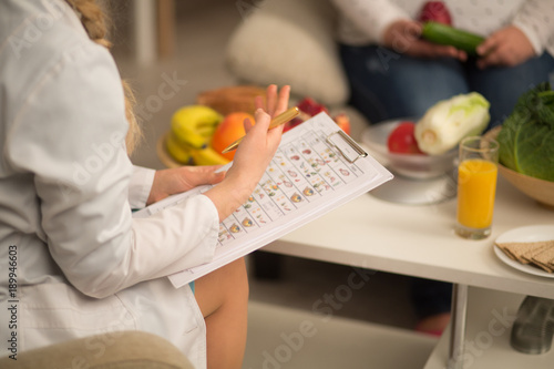 close up image of dietitian in white gown. holding die plan for patient.