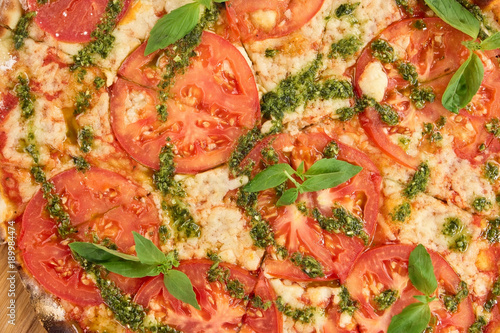 Close up sliced pizza with tomatoes, cheese and greens. Tomatoes pizza close up.