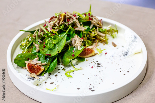 Salad with meat and figs lies on the plate