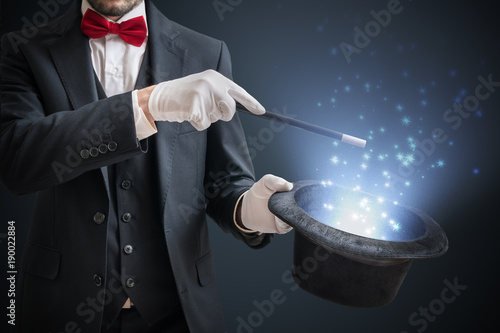 Magician or illusionist is showing magic trick. Blue stage light in background.