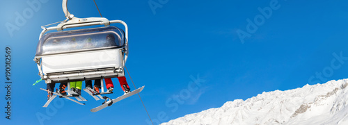 narciarze i snowboardziści w wyciągu narciarskim na tle błękitnego nieba. puste miejsce na tekst