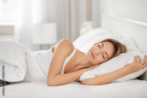 Young woman sleeping on white pillow in bed