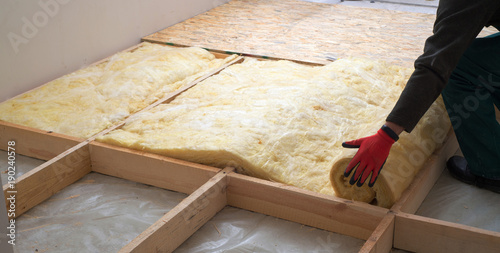 Work composed of mineral wool insulation in the floor, floor heating insulation , warm house, eco-friendly insulation, a builder at work