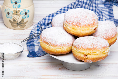 Tradycyjne polskie pączki z cukrem pudrem i nadzieniem na drewnianym tle, podawane w tłusty Czwartek