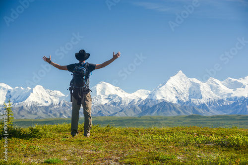 man with outstreched arms in front of Alaskan Range, Denali