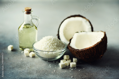 Coconuts products - milk, oil, shavings on grey concrete background. Copy space. Hair, skin and body treatment.