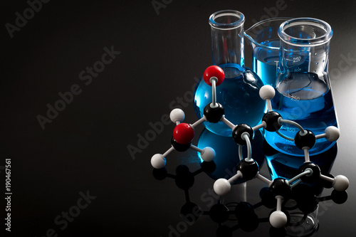 Organic chemistry, science class and STEM research concept with a methyl benzoate molecule on blue chemical solution in chemistry glassware, Erlenmeyer and Boiling (or Florence) flasks with copy space