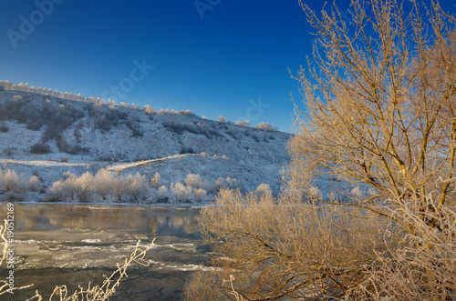 Freezing river from the hilly banks and large ice floes. A sunny day with a cloudless sky.