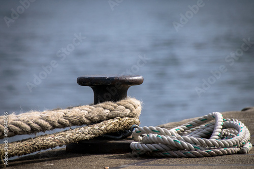 Ship mooring ropes secured around a port bollard