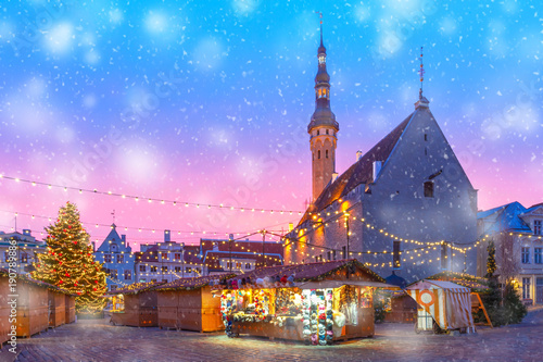 Decorated and illuminated Christmas tree and Christmas Market at Town Hall Square or Raekoja plats at beautiful snowy sunrise, Tallinn, Estonia.