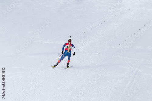 Biathlon racing, biathlete skiing with rifle on his back