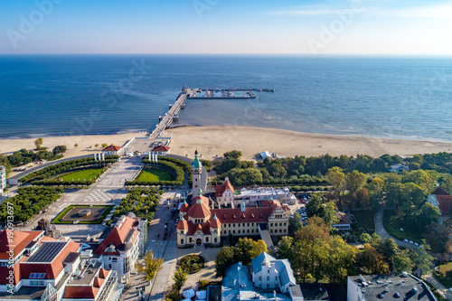 Sopot resort in Poland. SPA, old lighthouse, wooden pier (molo) with marina, yachts, beach, vacation infrastructure, park, promenade and walking people. Aerial view.