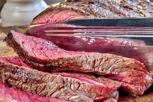 Fried meat with blood with hunting knife. Well done steak closeup. Rustic style.