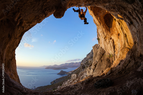 Young man lead climbing on ceiling in cave