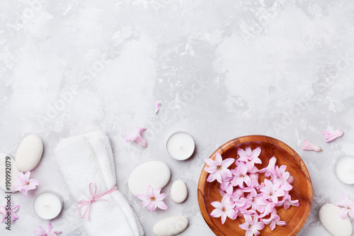 Spa, aromatherapy, beauty background with massage pebble, perfumed flowers water and candles on stone table top view. Relaxation and zen like concept. Flat lay.