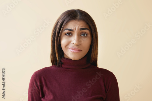 Studio shot of beautiful young African American female employee with dark straight hair having displeased upset look, feeling frustrated and stressed while having problems and failures at work