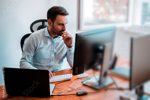 Concentrated businessman analyzing graphs in his office at computer.