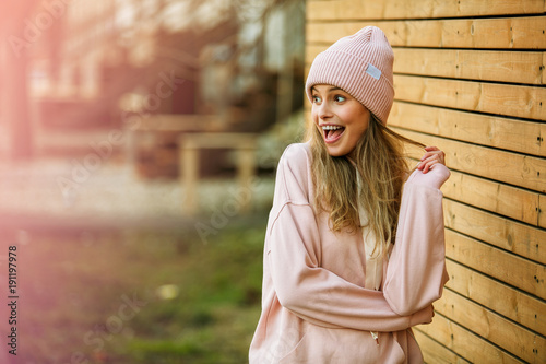 cool young woman in pink hoodie on wooden background