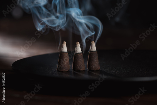 three burning incense sticks with blue smoke
