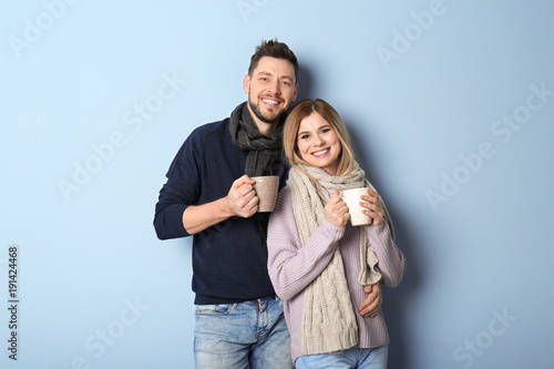 Young couple in warm clothing on color background. Ready for winter vacation