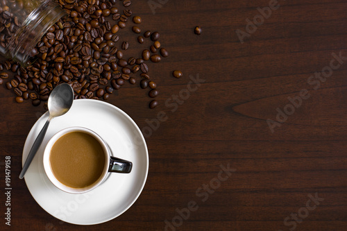 Cup of coffee from above, lay flat image, with coffee beans on wood table.