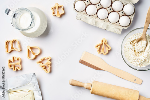 Objects and ingredients for baking, plastic molds for cookies on a white background. Flour, eggs, rolling pin, milk, butter, cream. Top view, space for text